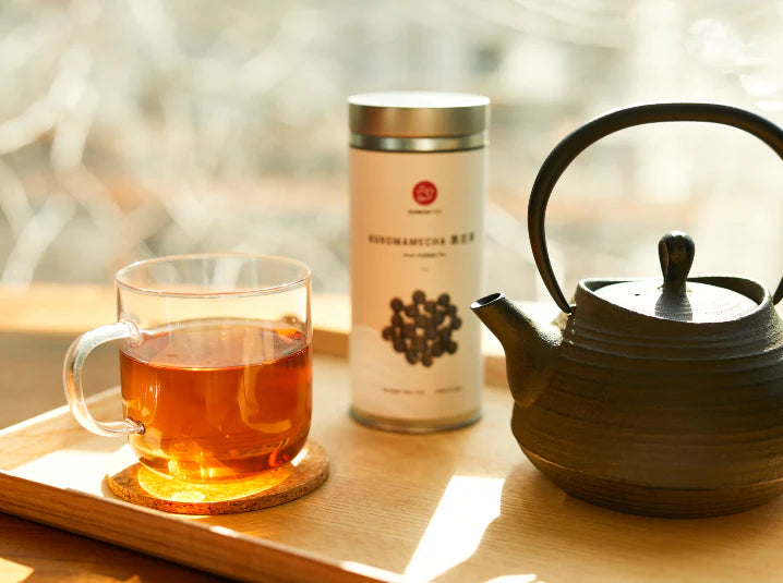 Cozy lifestyle scene with a mug of kuromamecha herbal tea beside a traditional Japanese tetsubin teapot in a warm fall setting