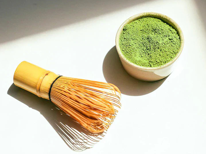matcha bamboo whisk chasen next to organic japanese green tea powder