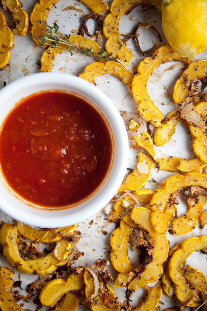 Parmesan roasted delicata squash on baking sheet with cup on marinara sauce.