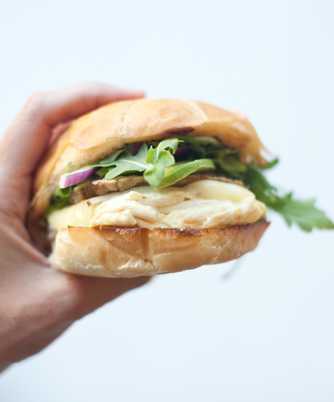 Hand holding macro-friendly egg sandwich with lemon garlic aioli.