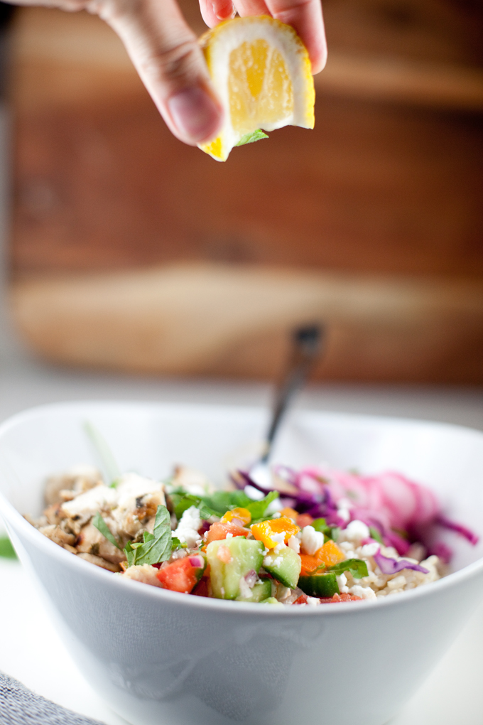Squeezing fresh lemon juice on top of cava copycat mediterranean grain bowl.