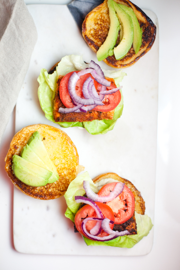 View from the top of two open faced salmon sandwiches topped with tomatoes and onion