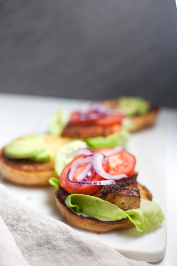 Two salmon sandwiches with the top bun off and a gray background