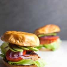 Two blackened salmon sandwiches on a white surface