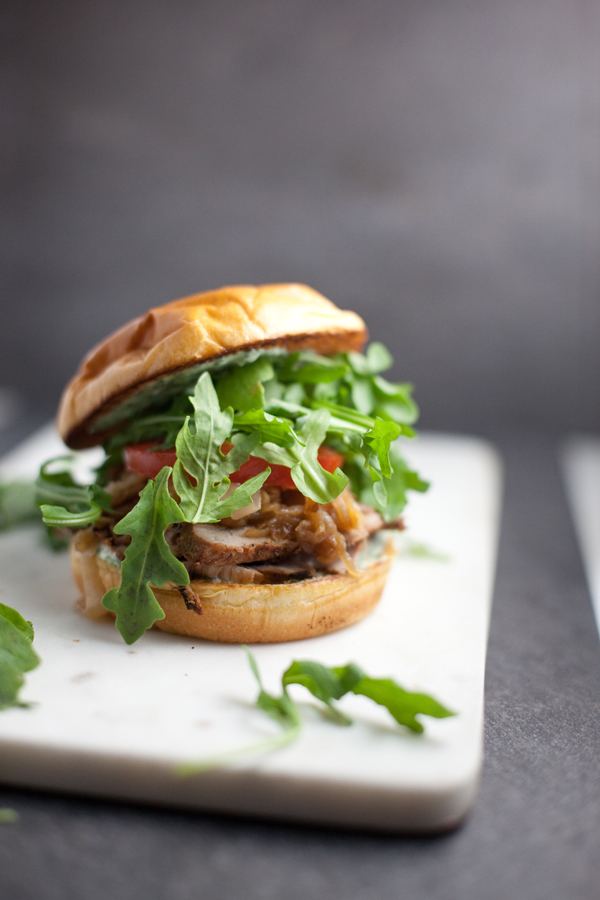 Pork Tenderloin Sandwich with lots of arugula on a cutting board.
