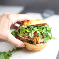 Pork Tenderloin Sandwich with lots of arugula being held