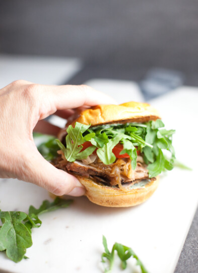 Pork Tenderloin Sandwich with lots of arugula being held
