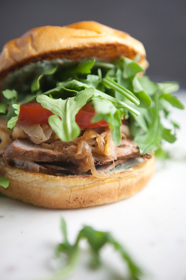 Pork Tenderloin Sandwich with lots of arugula on a cutting board
