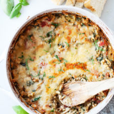Cheesy spaghetti squash bake in one pan with a wooden spoon.