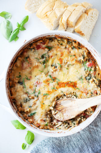 Cheesy spaghetti squash bake in one pan with a wooden spoon.