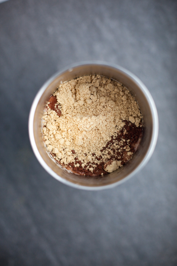 Chocolate protein shake in a large metal tumbler with powdered peanut butter on top.