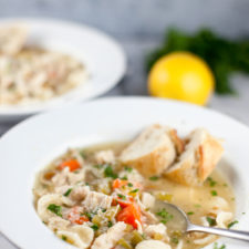 Two bowls of chicken soup with bread