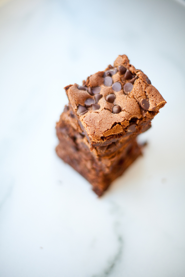 Three stacked chocolate brownies with chocolate chips on top, placed on a white marble surface—truly the best brownies ever.