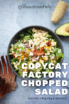 A bowl of Copycat Factory Chopped Salad with corn, avocado, tomatoes, and cheese sits on a blue surface. Wooden salad tongs, half an avocado, and a piece of corn are nearby. Text reads: Copycat Factory Chopped Salad Macro-Friendly Dinner.