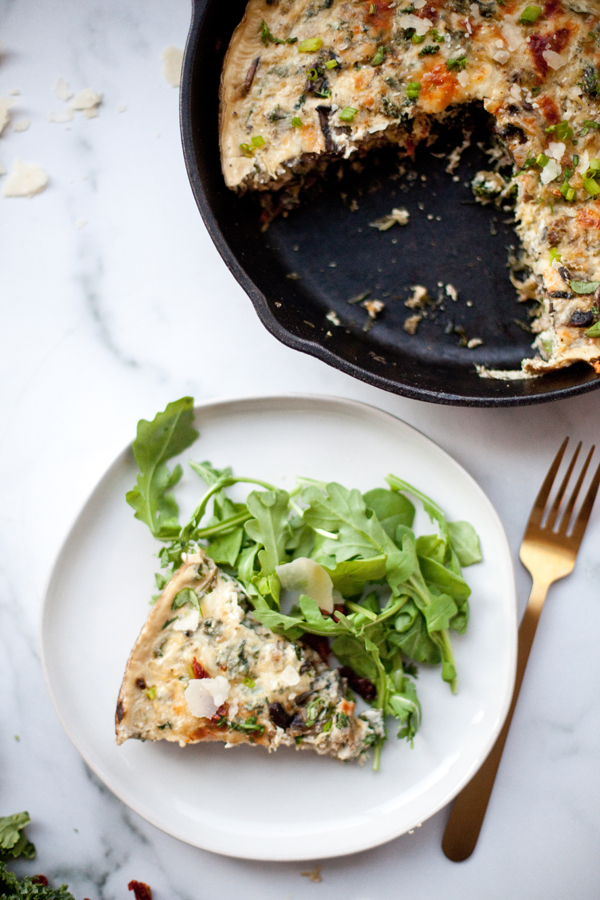 Slice of turkey mushroom quiche served on a plate with arugula.