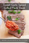 Sliced sweet garlic spiced grilled flank steak rests on a wooden board, garnished with parsley. A spoon holds chunky red sauce above the steak. Text reads: Sweet Garlic Spiced Grilled Flank Steak. Website: www.lillieeatsandtells.com.