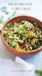 A wooden bowl filled with fresh and easy corn salsa, featuring colorful chopped vegetables and cilantro, sits on a light surface. Text above reads Fresh and Easy Corn Salsa. Website lillieeatsandtells.com appears at the bottom.