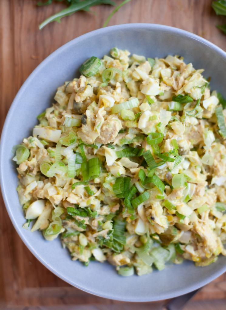 Quick pickle chicken salad garnished with green onions in gray bowl on top of wooden cutting board.