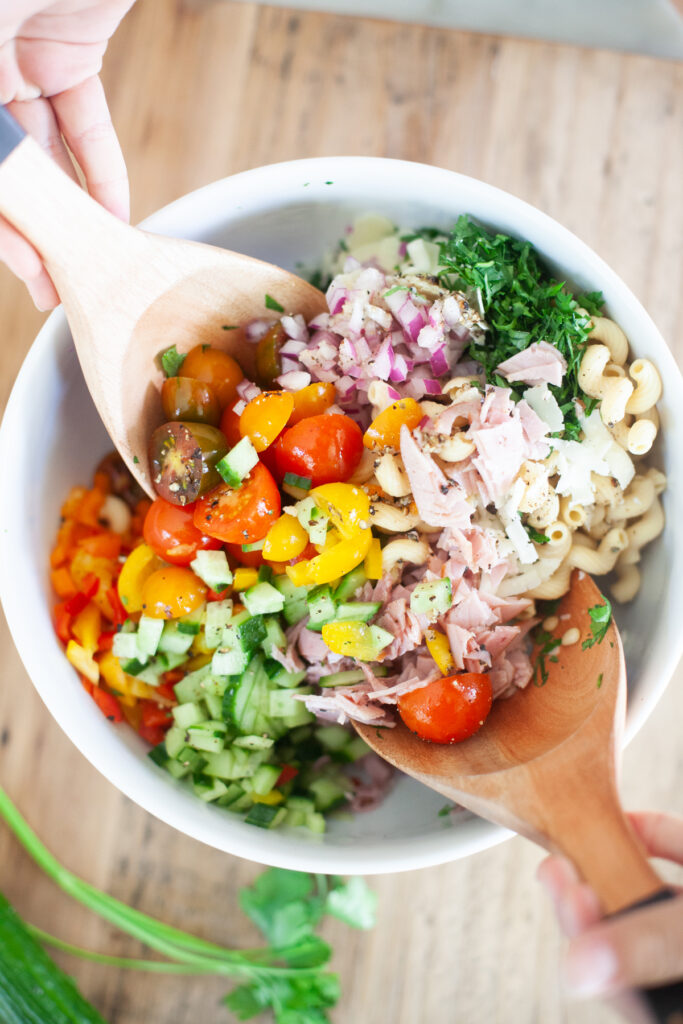 mixing Italian Pasta salad found at www.lillieeatsandtells.com