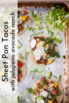Sheet pan with four Sheet Pan Tacos with Jalapeno Avocado Ranch, topped with ground meat, lettuce, radish slices, tomatoes, cilantro, and a vibrant green jalapeño avocado ranch sauce. Text on left reads: Sheet Pan Tacos with Jalapeno Avocado Ranch.