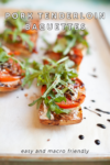 Sliced baguettes topped with pork tenderloin, tomato, arugula, and a balsamic drizzle on a parchment-lined baking sheet. Inspired by Pear Blue Cheese and Pork Baguettes, these Pork Tenderloin Baguettes are easy to make and macro friendly.