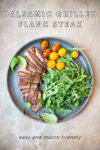 A plate with sliced Balsamic Grilled Flank Steak, arugula, yellow and red cherry tomatoes, and fresh basil leaves. Text reads: Balsamic Grilled Flank Steak. Easy and macro friendly.