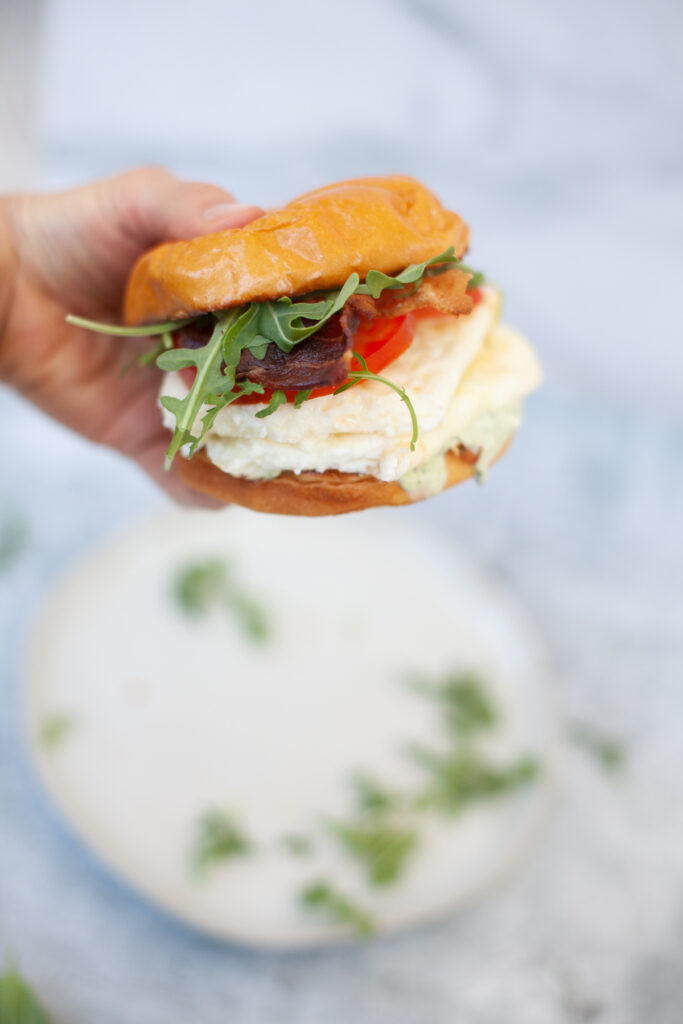 Hand holding an assembled tuscan egg white sandwich.