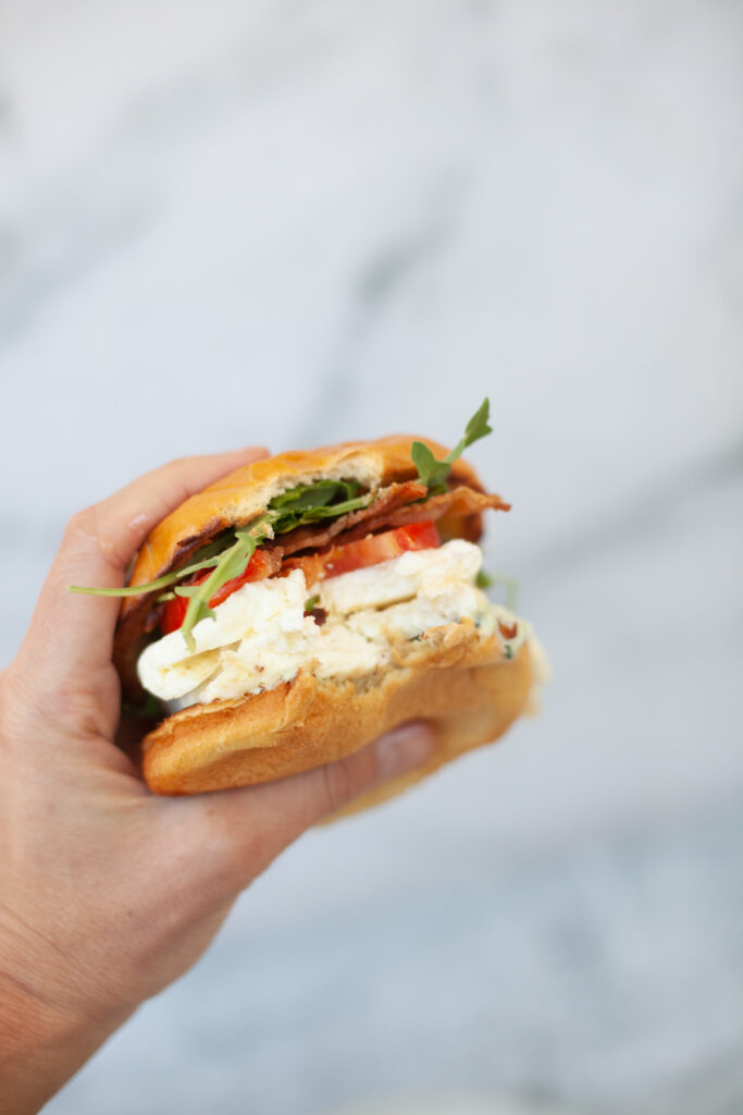Hand holding Tuscan Egg White Sandwich.