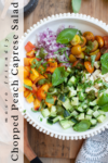 A bowl with chopped yellow and red heirloom tomatoes, peaches, red onions, cucumbers, basil, and pesto sauce—this vibrant Chopped Peach Caprese Salad is bursting with fresh flavors. Text on the image reads macro friendly Chopped Peach Caprese Salad.