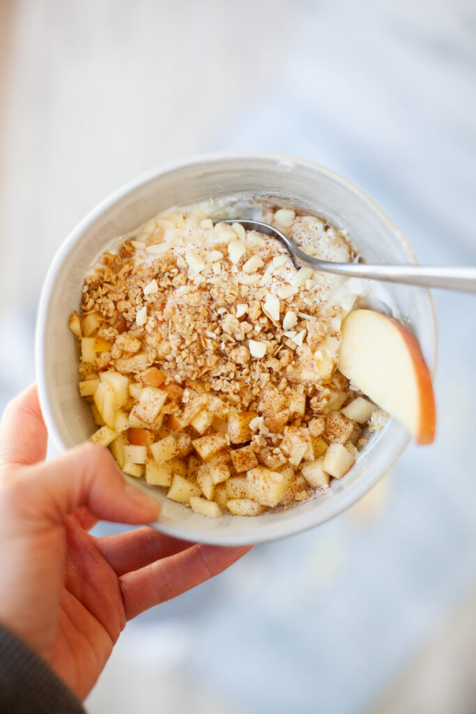 Apple crisp yogurt and cottage cheese bowl with toppings and spoon in the bowl.