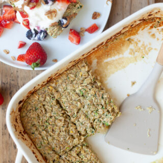 Baking dish of zucchini baked oats beside plate with slice of oats with toppings.
