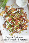 A tray of Macro Friendly Loaded Smashed Potatoes topped with bacon, green onions, cheese, and ranch dressing; a dish of dip and green onions are nearby. Text at the bottom reads: Easy & Delicious Loaded Smashed Potatoes.
