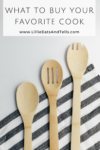 Three wooden kitchen utensils rest on a black and white striped cloth, with text above reading What to Buy Your Favorite Cook www.LillieEatsAndTells.com—showcasing kitchen favorites every cook will love.