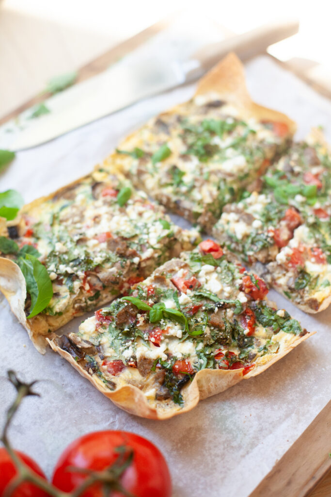Garden veggie quiche cooked and sliced on parchment paper.