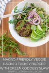A bowl with a Veggie Packed Turkey Burger with Green Goddess Slaw, sliced avocado, red onion, fresh greens, slaw, and parsley. A fork rests on the bowl. Text overlay: Macro-friendly Veggie Packed Turkey Burger with Green Goddess Slaw.