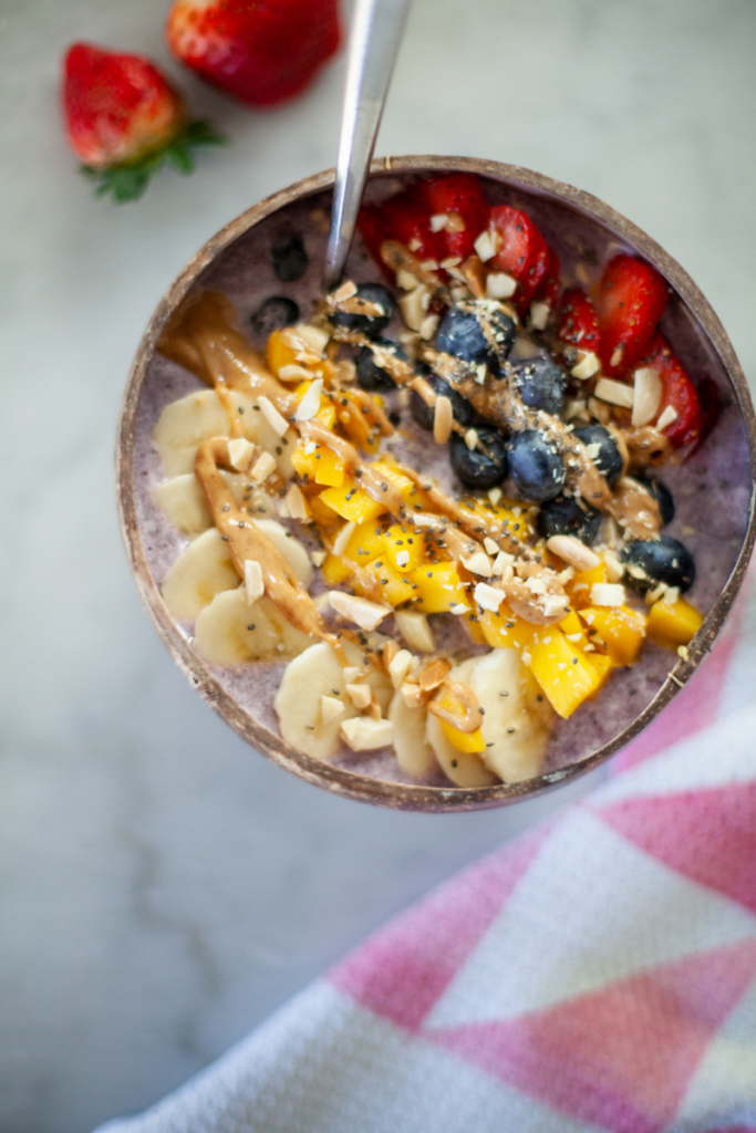Spoon digging into high protein smoothie bowl in a bowl with spoon.