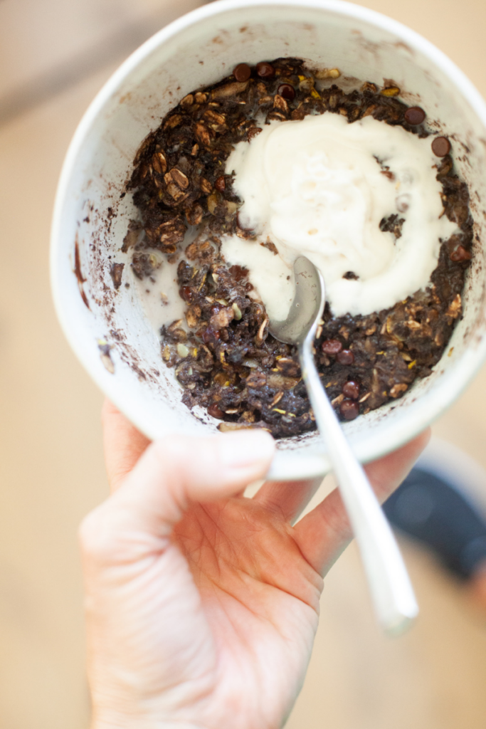 Microwave zucchini brownie oats in bowl with reddi whip and spoon.