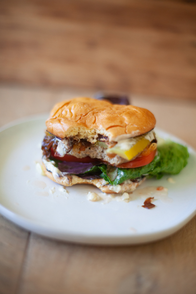 Bacon cheeseburger with a large bite taken out of it.