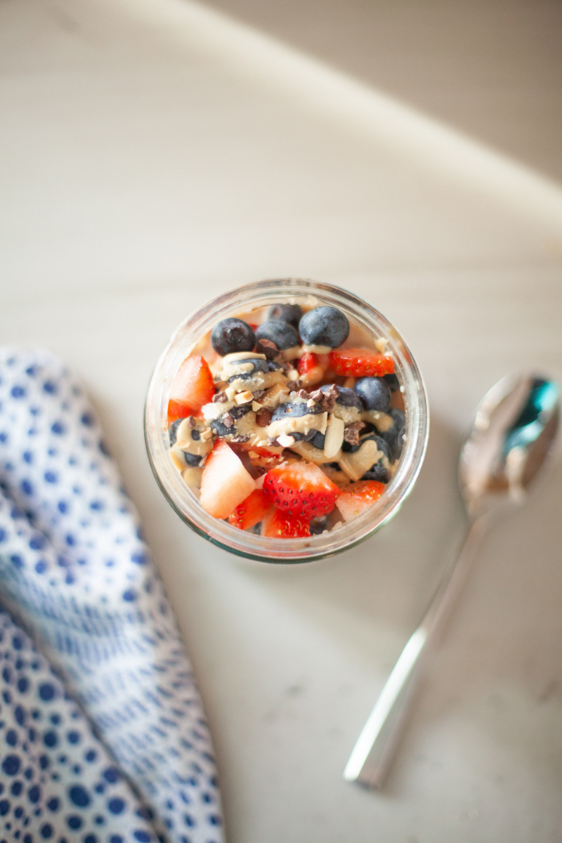 Macro-friendly, filling cauliflower oats with toppings in a jar and a spoon to the side.
