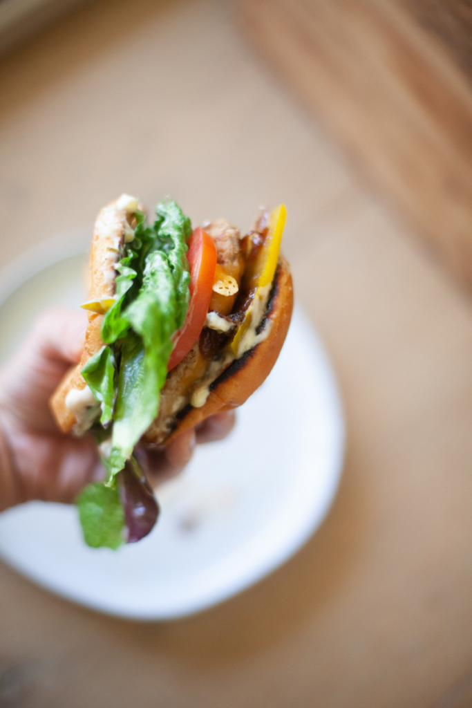 Assembled bacon burger topped with tomato, lettuce, and cheese.
