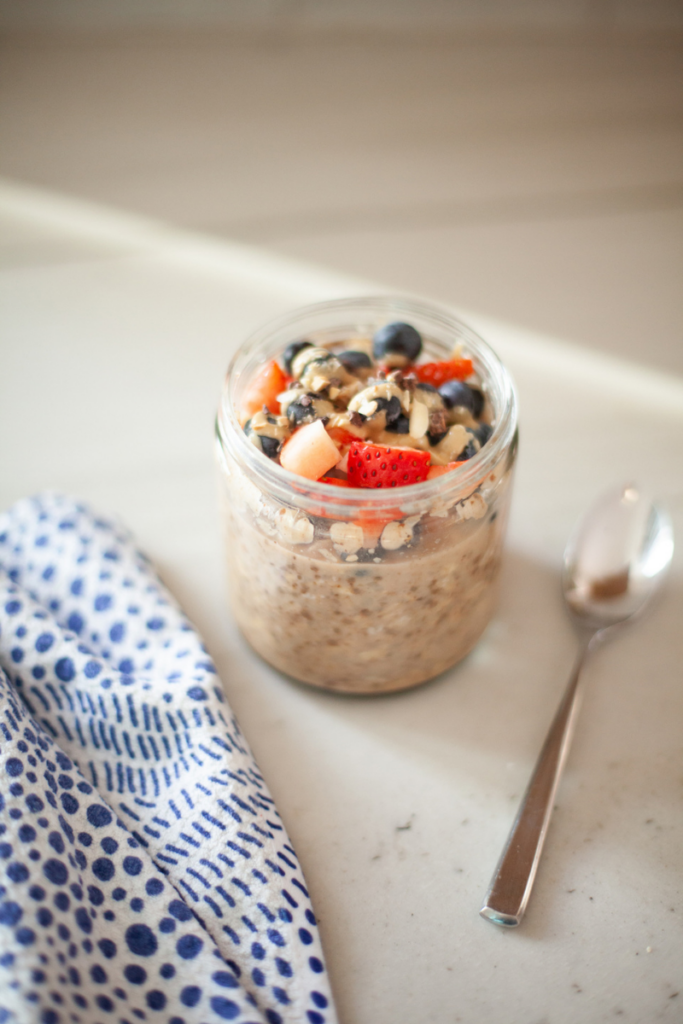 Overnight cauliflower oats in a jar with toppings and a spoon on the side.
