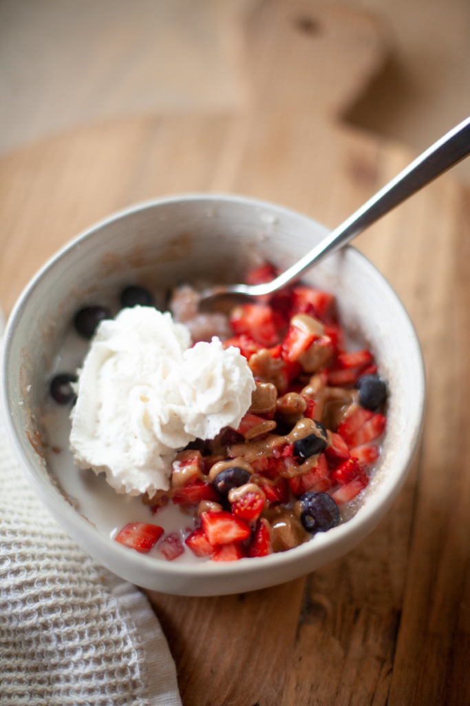 Cream of rice breakfast bowl topped with fresh berries, almond whip and nut butter.