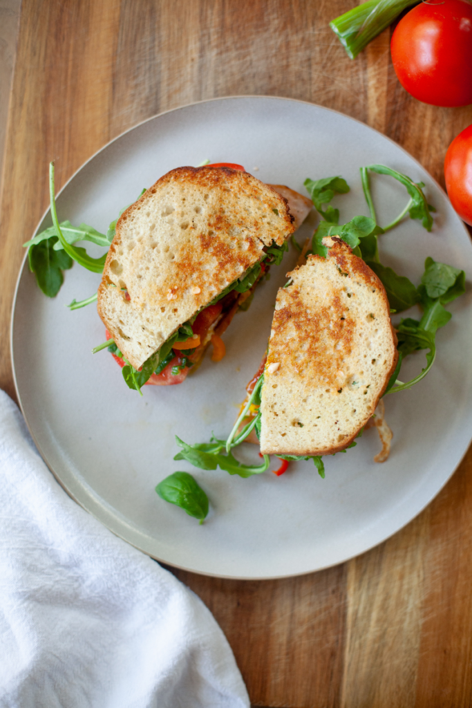 Fried egg blt cut into two halves on a plate.