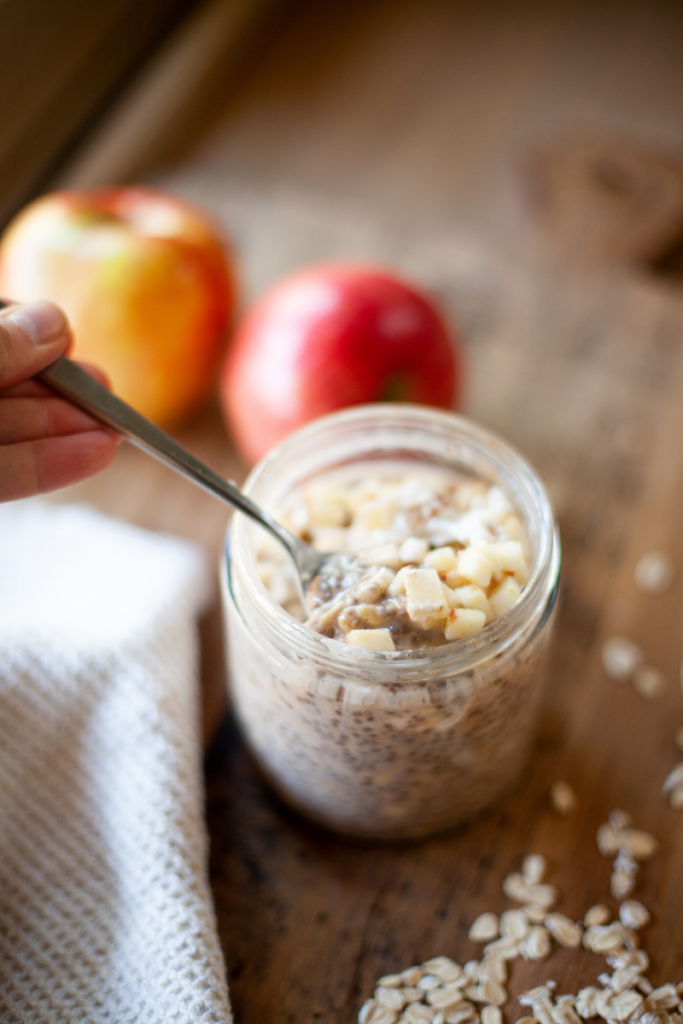Spoon digging into apple pie overnight oats.
