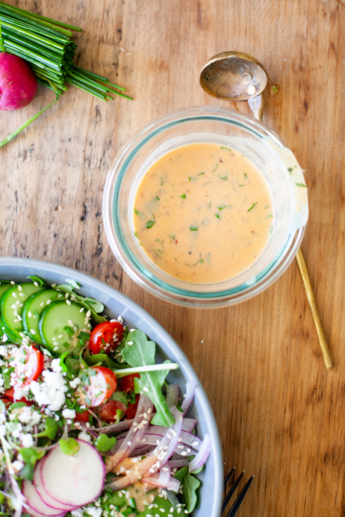 Creamy honey chipotle vinaigrette in a glass bowl next to a salad.