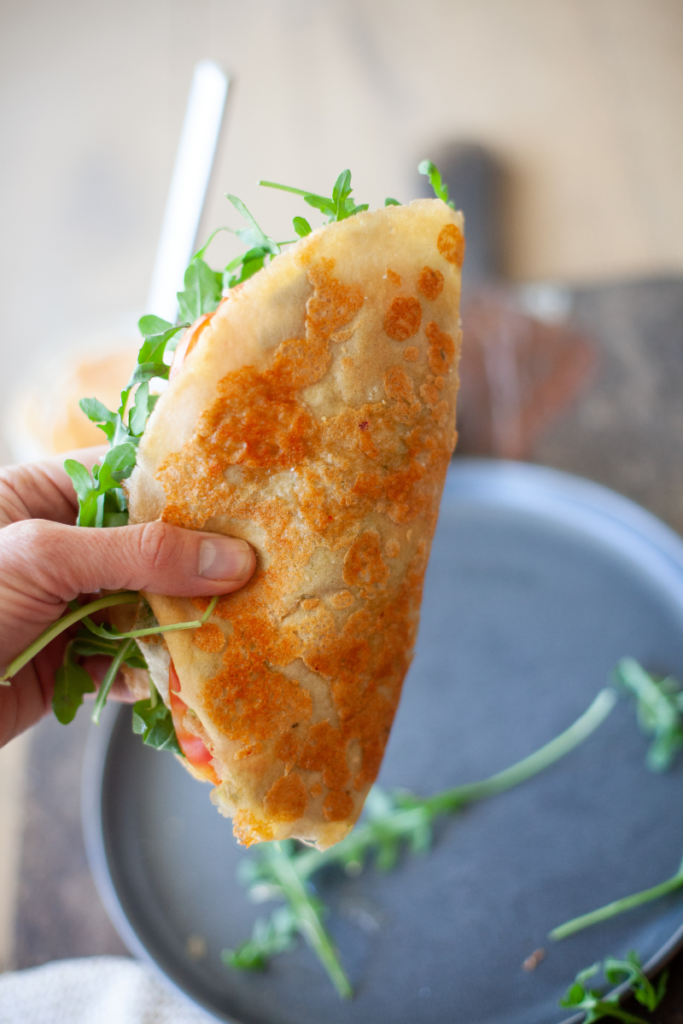 Hand holding cheese-fried egg wrap.