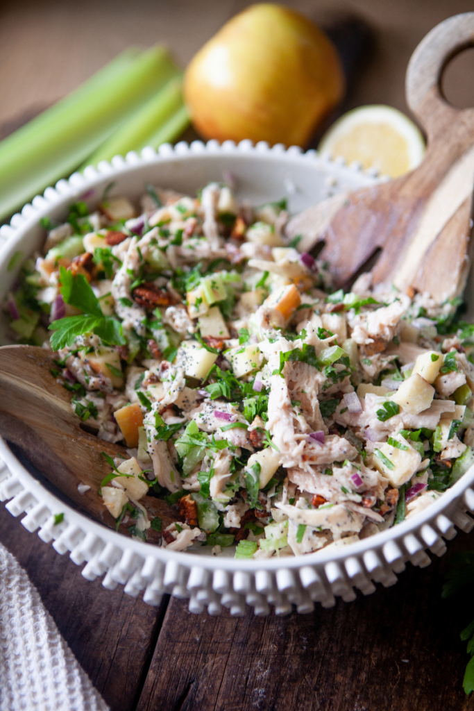 Waldorf chicken salad in large mixing bowl with wooden mixing spoon.