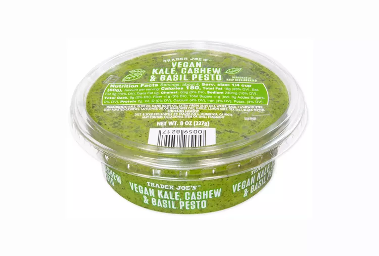 A clear plastic container of Trader Joe’s Vegan Kale, Cashew & Basil Pesto, showing the vibrant green pesto inside and labeled with product information on the lid and side—one of My Favorite Trader Joe’s Products.