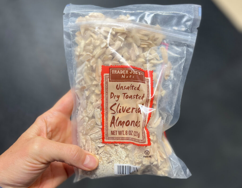 A hand holds a clear bag of Trader Joe’s Unsalted Dry Toasted Slivered Almonds, 8 oz, with visible almond slivers inside—one of My Favorite Trader Joe’s Products.
