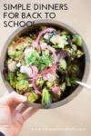 A hand holds a bowl of salad with leafy greens, radishes, pickled onions, avocado, feta, and herbs. Text reads, Simple back to school dinner ideas. Website: lillieeatsandtells.com.